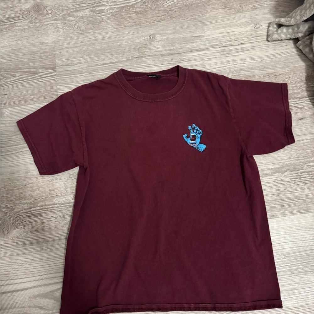 This is a maroon/red Santa Cruz shirt with a blue hand in the back.